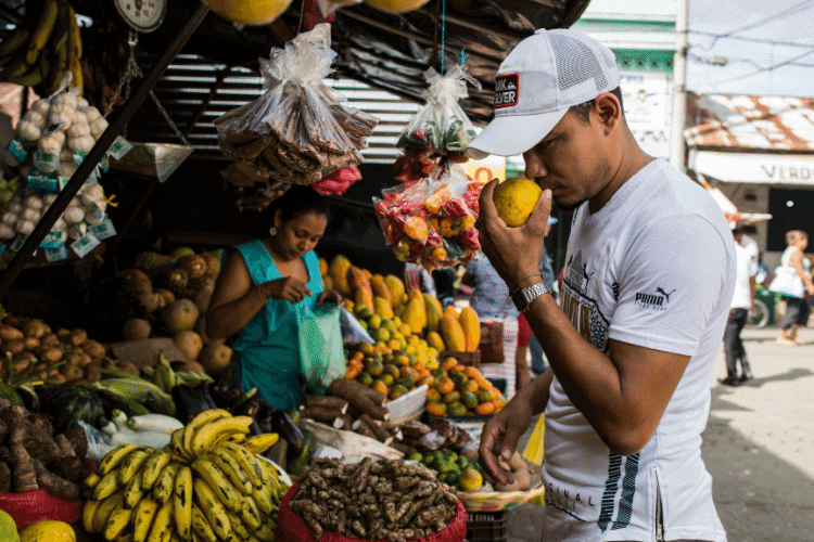 man smelling fruit at street market 